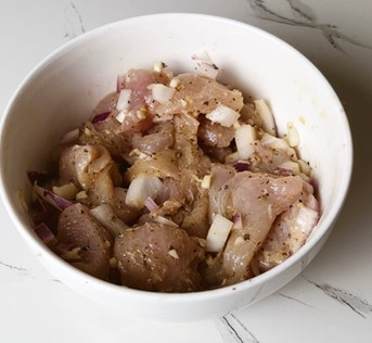 Marinated chicken fillet pieces coated in a flavorful herb and lemon marinade, ready for cooking.