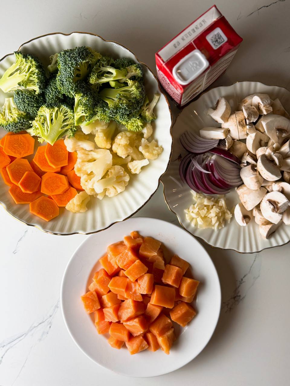 Fresh salmon fillets with fresh vegetables, garlic, onion and cream, ready for cooking.