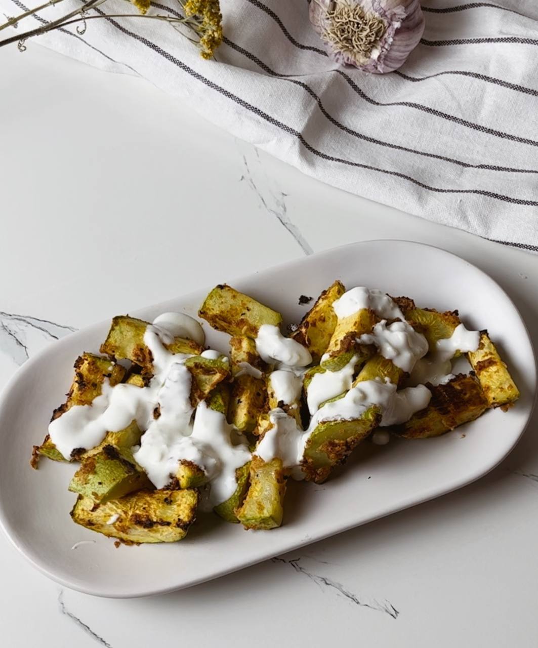 Crispy baked zucchini sticks drizzled with creamy Greek yogurt dip.