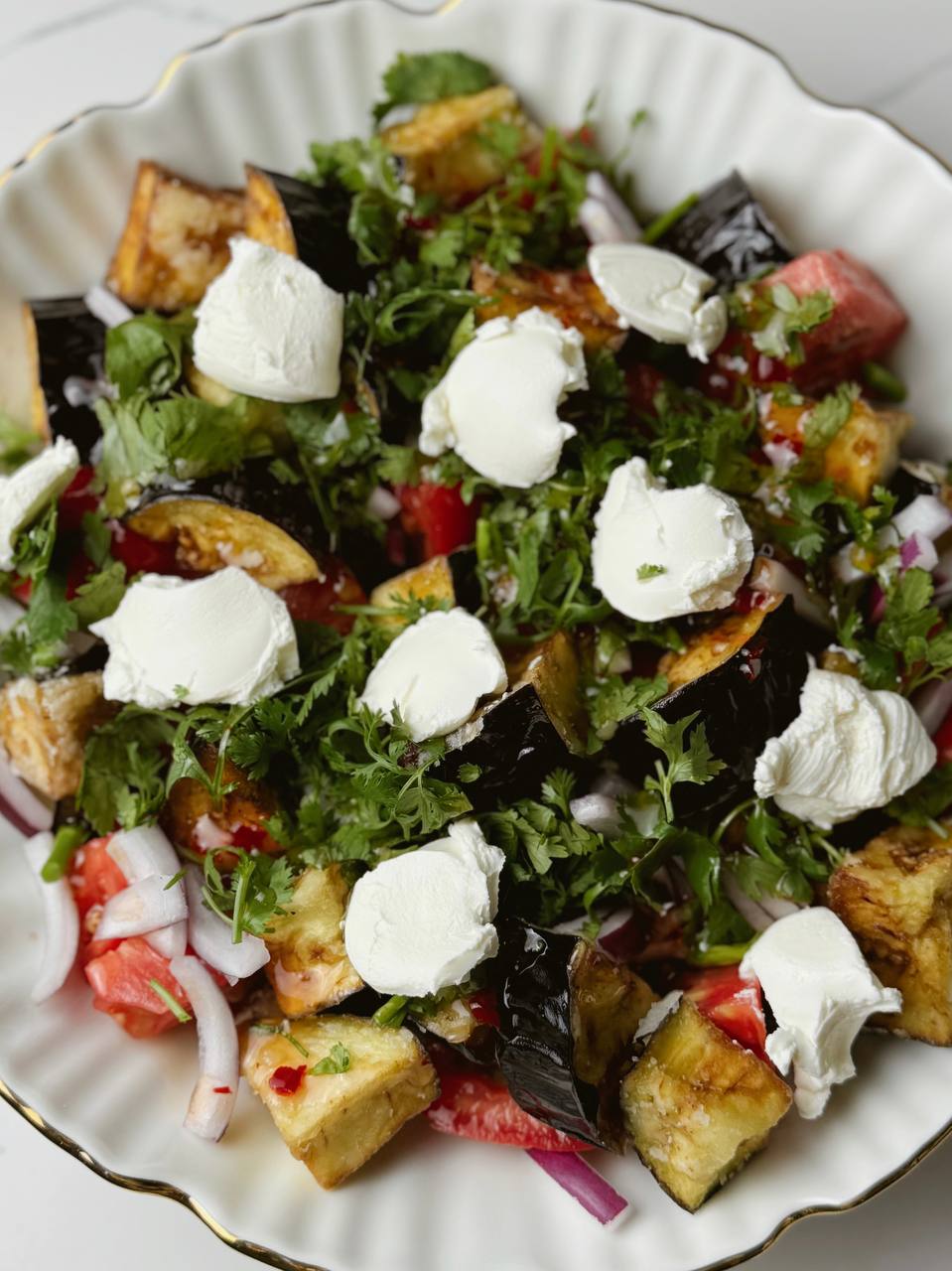 Crispy eggplant salad served with sweet chili sauce, cottage cheese, and fresh herbs, top-down view.
