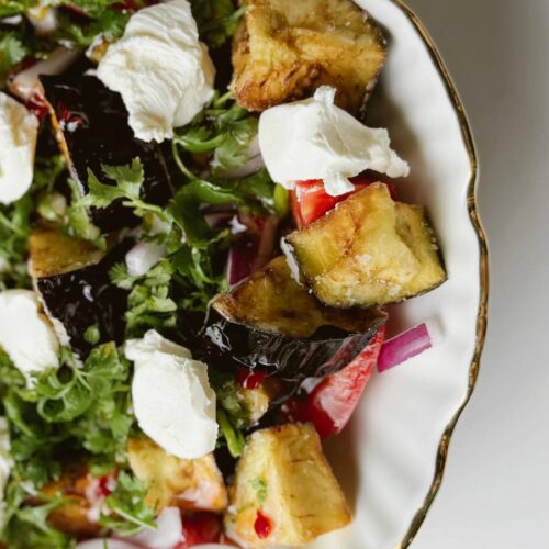 Close-up of crispy eggplant salad with sweet chili sauce, cottage cheese, and fresh herbs.