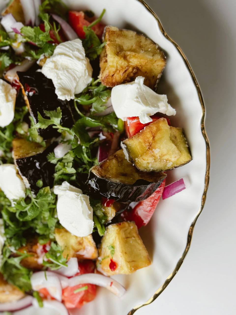 Close-up of crispy eggplant salad with sweet chili sauce, cottage cheese, and fresh herbs.