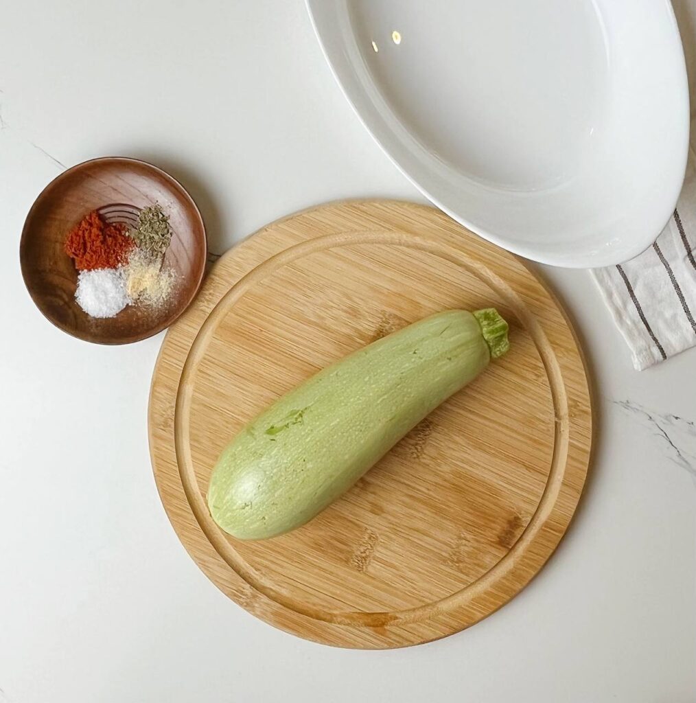 Fresh whole zucchini on a wooden board with spices and seasonings.