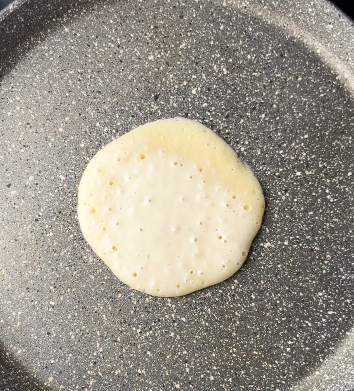 A fluffy pancake with bubbles being flipped