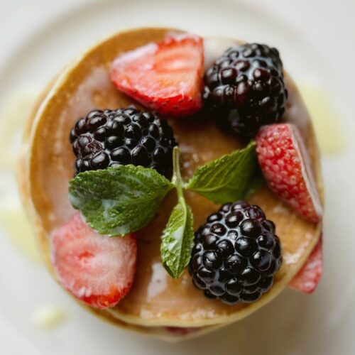 A plate of pancakes topped with fresh berries and mint