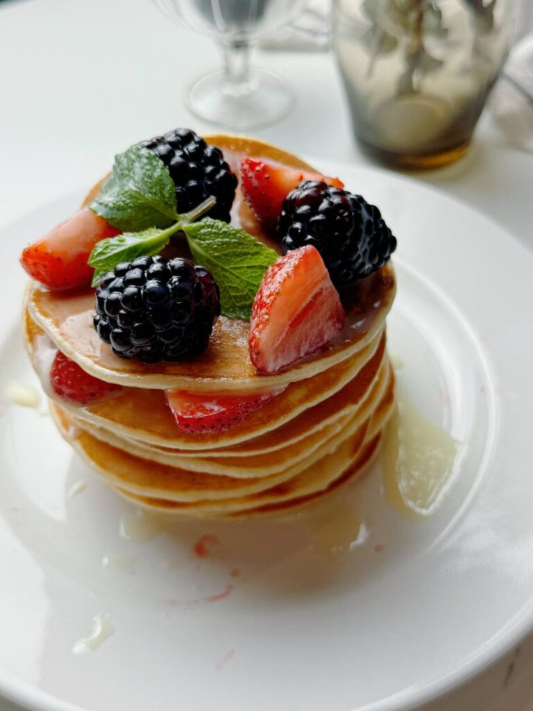 A tall stack of fluffy pancakes drizzled with condensed milk