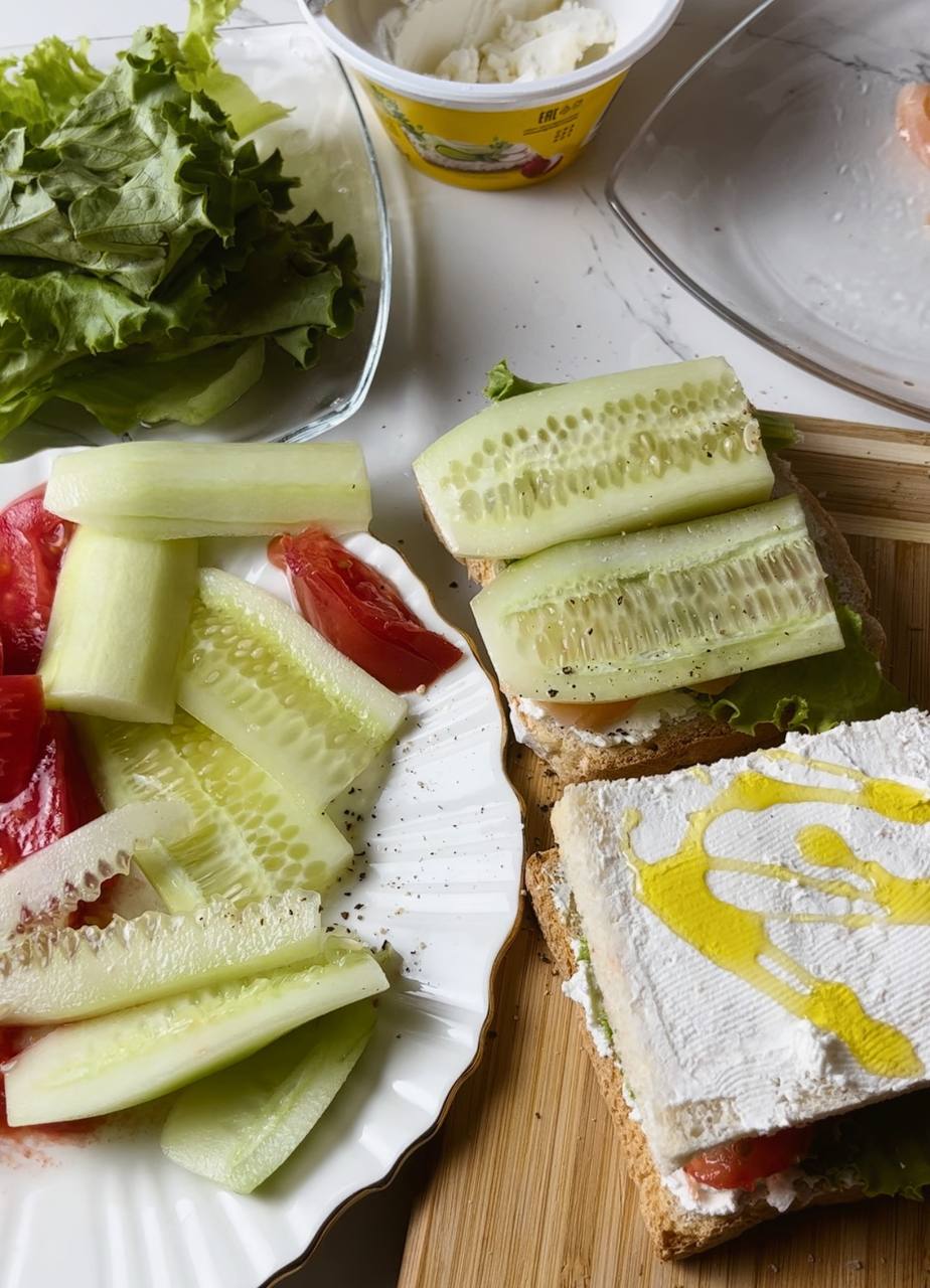 Assembling a salmon club sandwich with layers of ingredients.