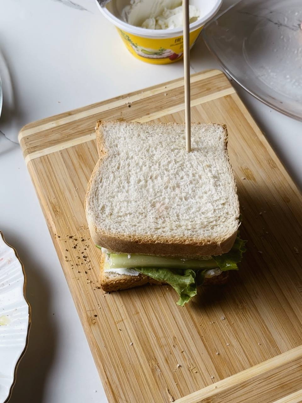 A whole salmon club sandwich held together with a wooden stick.
