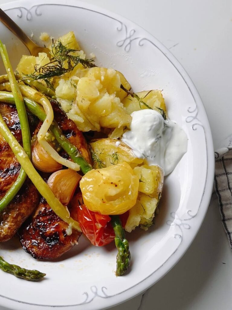 Close-up shot of crispy roasted potatoes, grilled chicken, and asparagus on a plate.