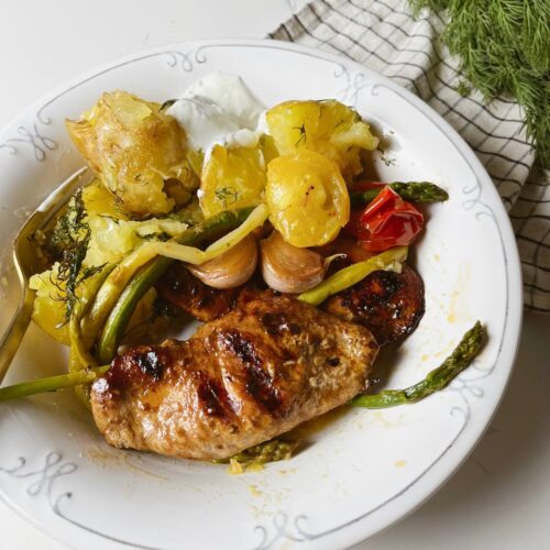 A plated meal of crispy roasted potatoes, grilled chicken, and sautéed asparagus.