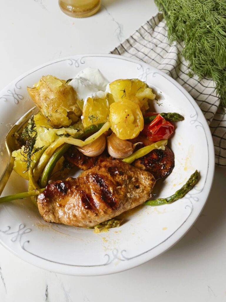 A plated meal of crispy roasted potatoes, grilled chicken, and sautéed asparagus.