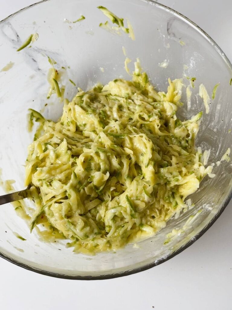 Potato and zucchini pancake batter mixed in a bowl.