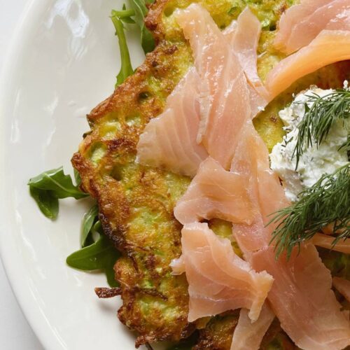A close-up of a potato zucchini pancake with creamy garlic topping and smoked salmon