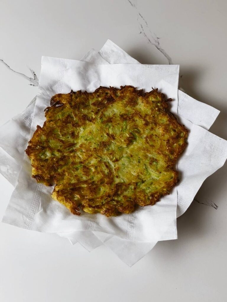 Freshly fried potato zucchini pancakes resting on a paper towel.