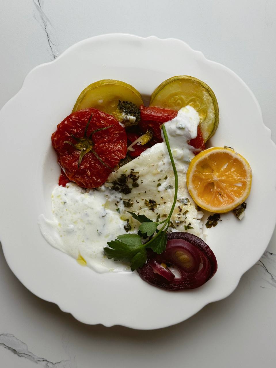 Baked cod with vegetables served with garlic yogurt sauce