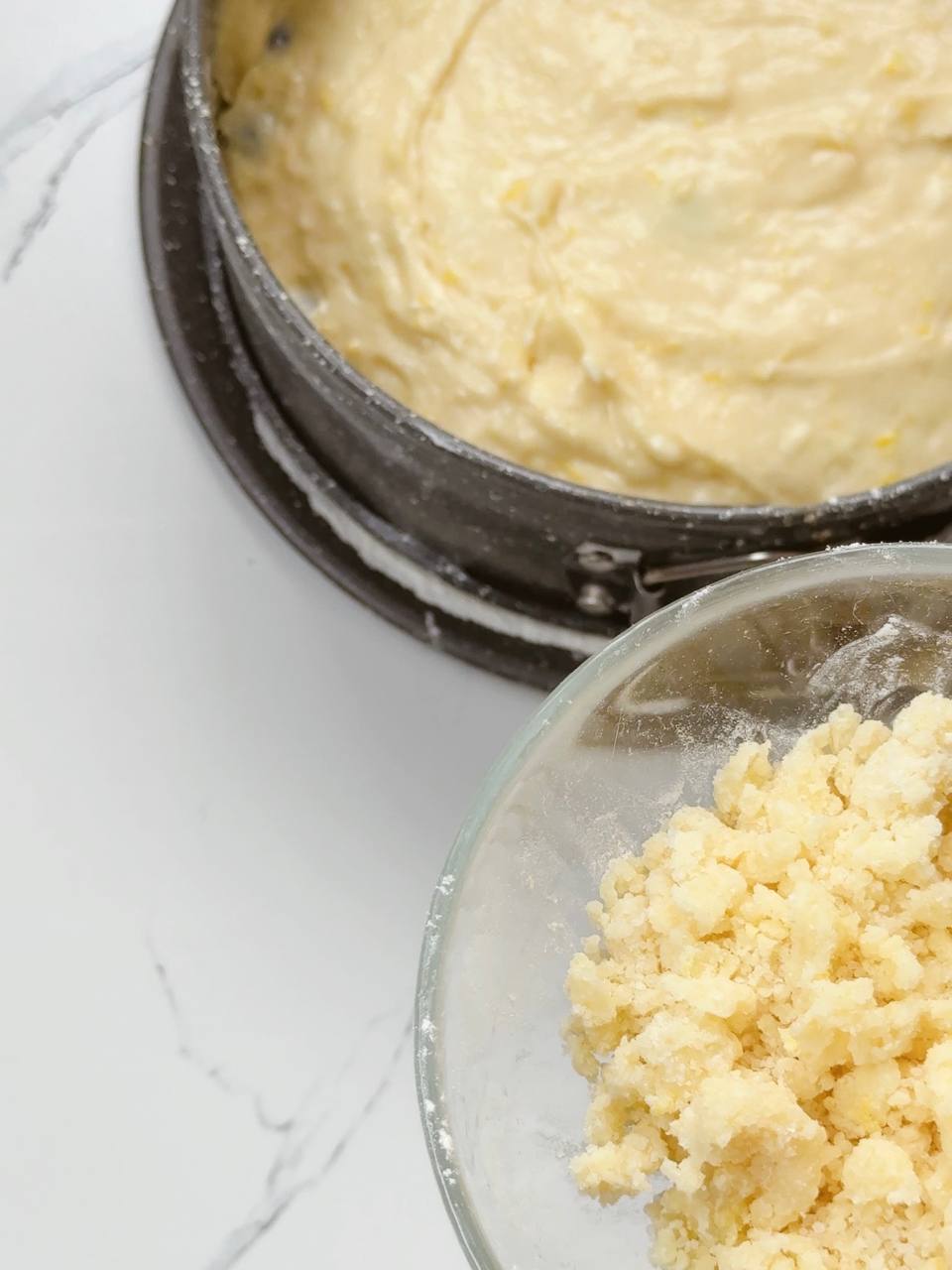 Lemon cake dough in pan with bowl of crumble topping on the side