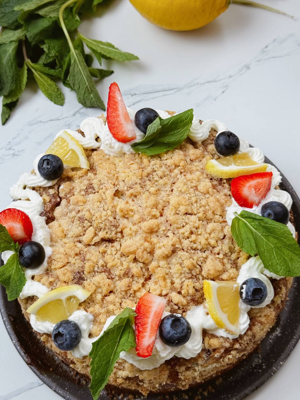 ull view of decorated lemon yogurt cake with blueberries and strawberries
