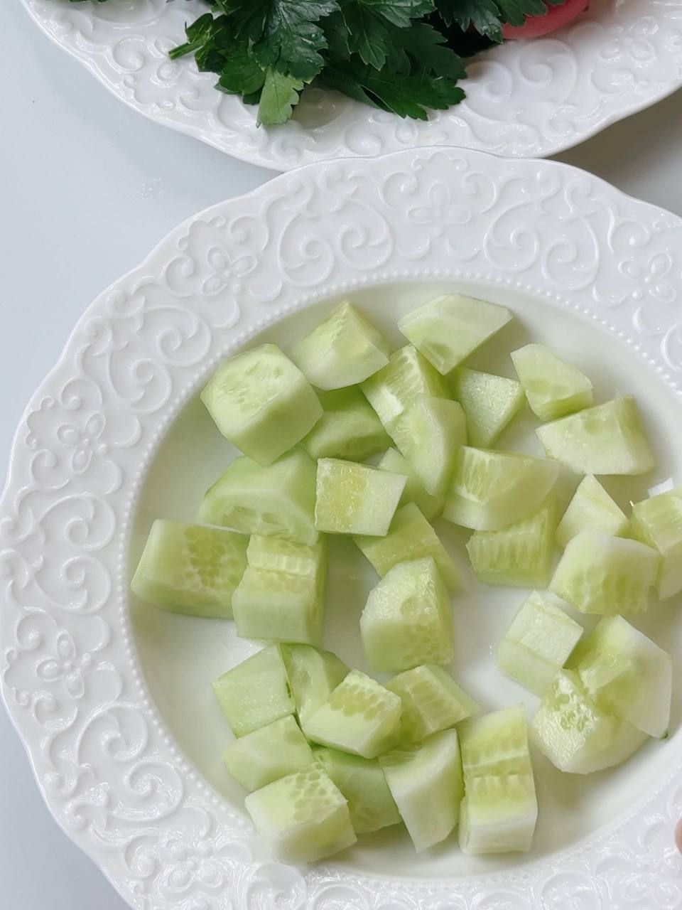 Peeled and chopped cucumber on a white plate for Shopski Salad