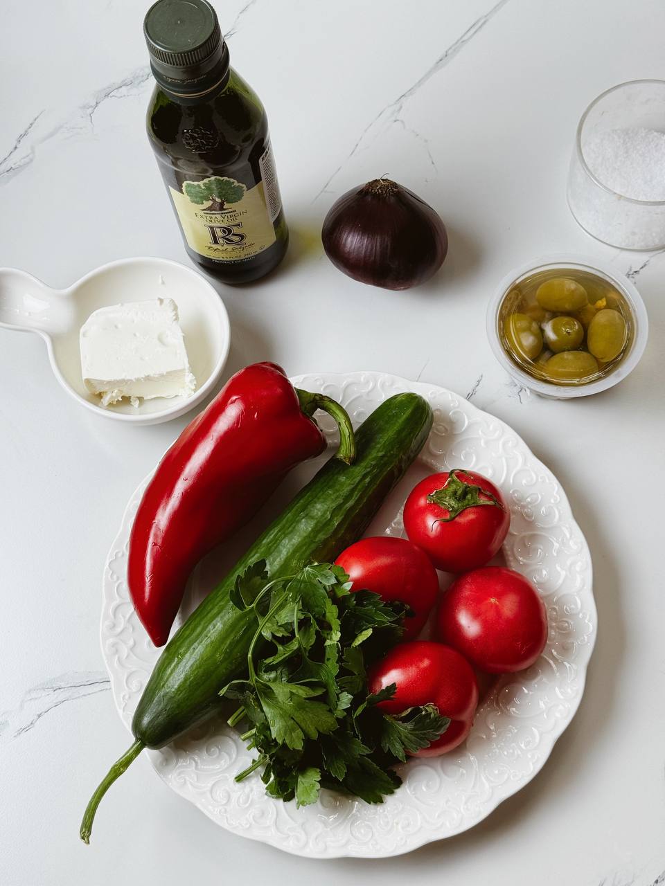 Fresh ingredients for Shopski Salad including tomatoes, cucumber, bell pepper, red onion, brynza, and olives