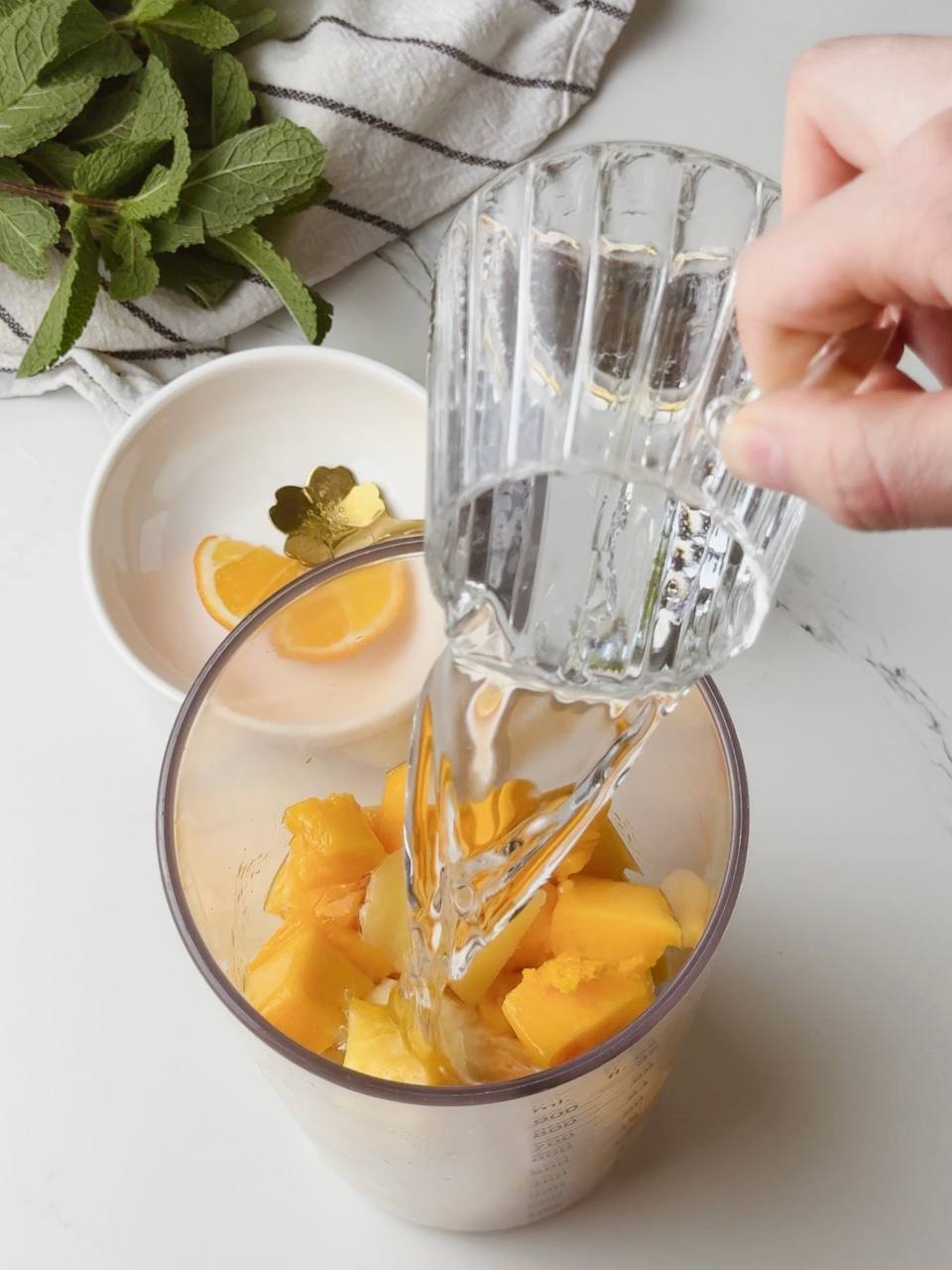Pouring water into blender cup for tropical smoothie