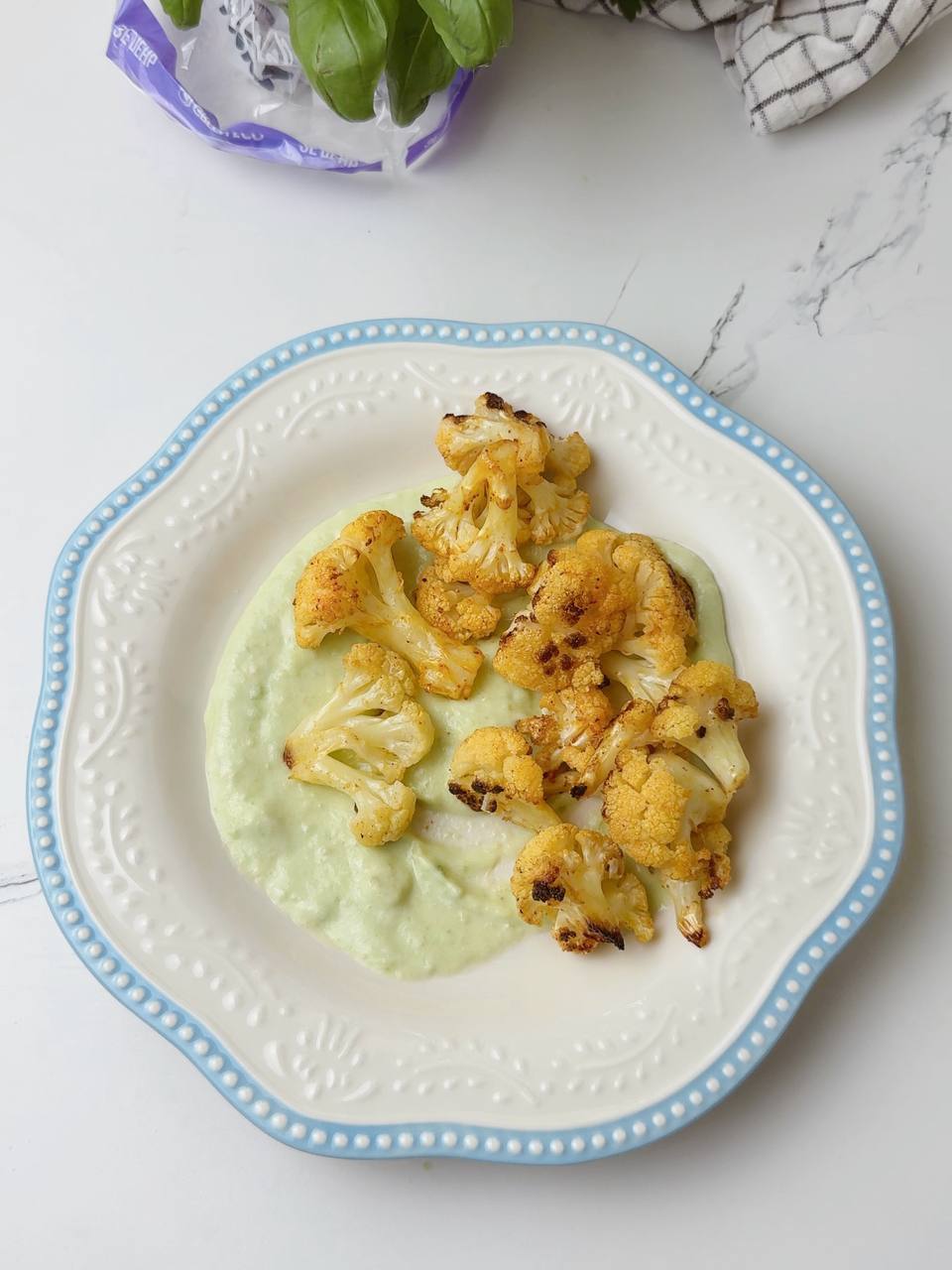 Plate with creamy avocado sauce served alongside roasted cauliflower