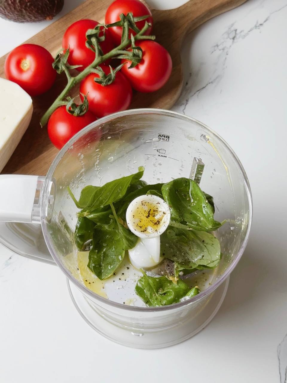Fresh basil, lemon juice, garlic, and olive oil in a blender ready to be blended into vinaigrette