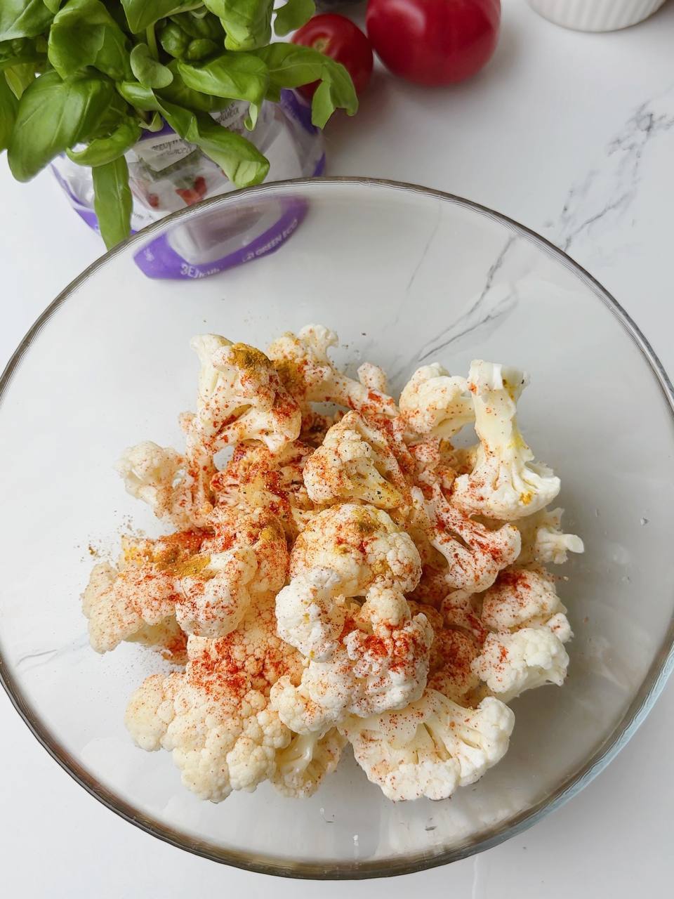 Cauliflower florets mixed with smoked paprika and turmeric in a bowl