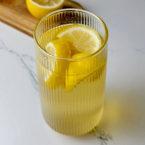 A glass of cold green tea with lemon and ice cubes