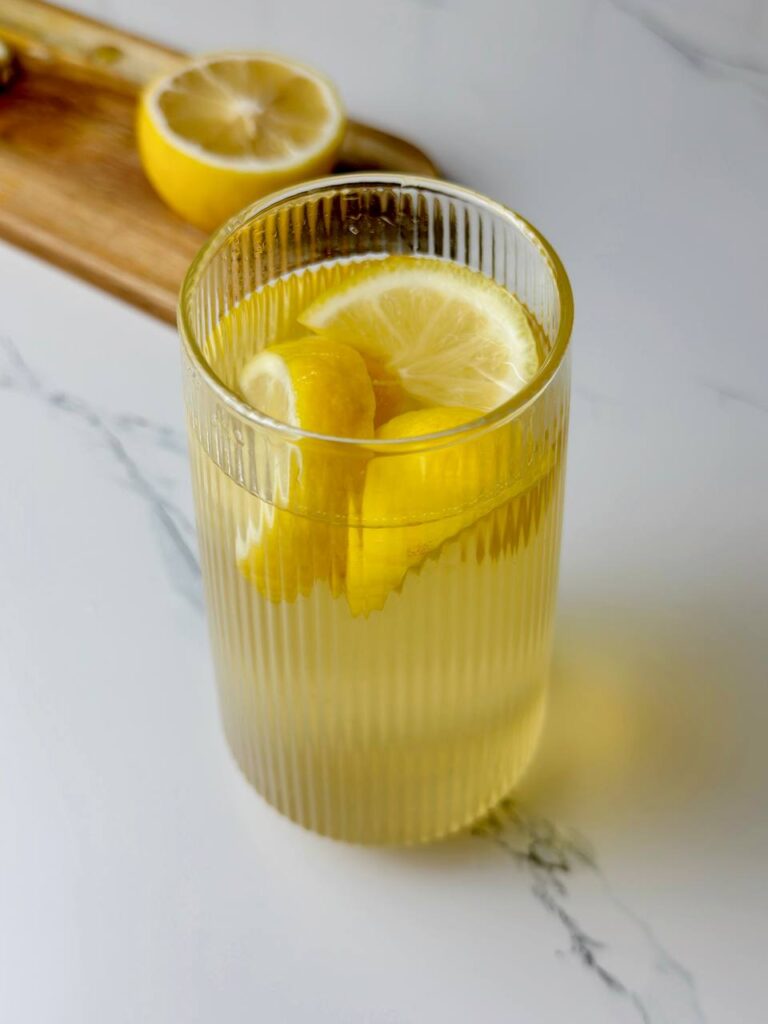 A glass of cold green tea with lemon and ice cubes