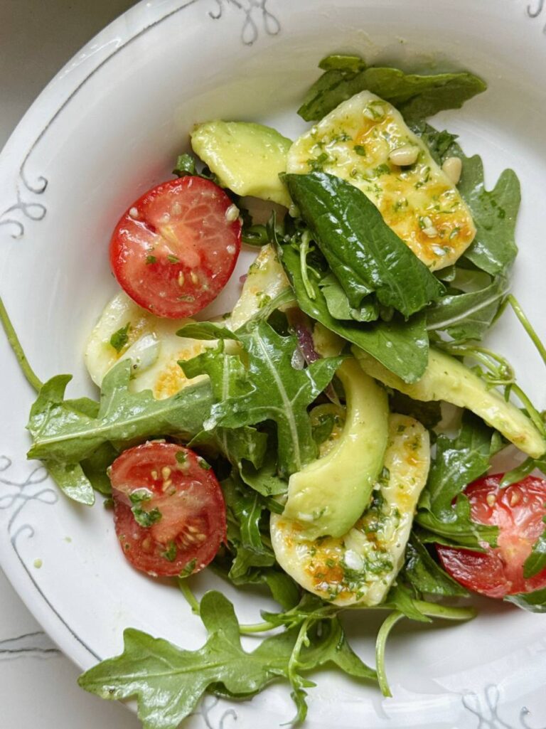 Close-up of grilled halloumi salad with golden cheese, colorful vegetables, and fresh herbs