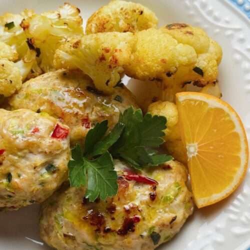 Close-up of fritters served with roasted cauliflower, lemon, and parsley