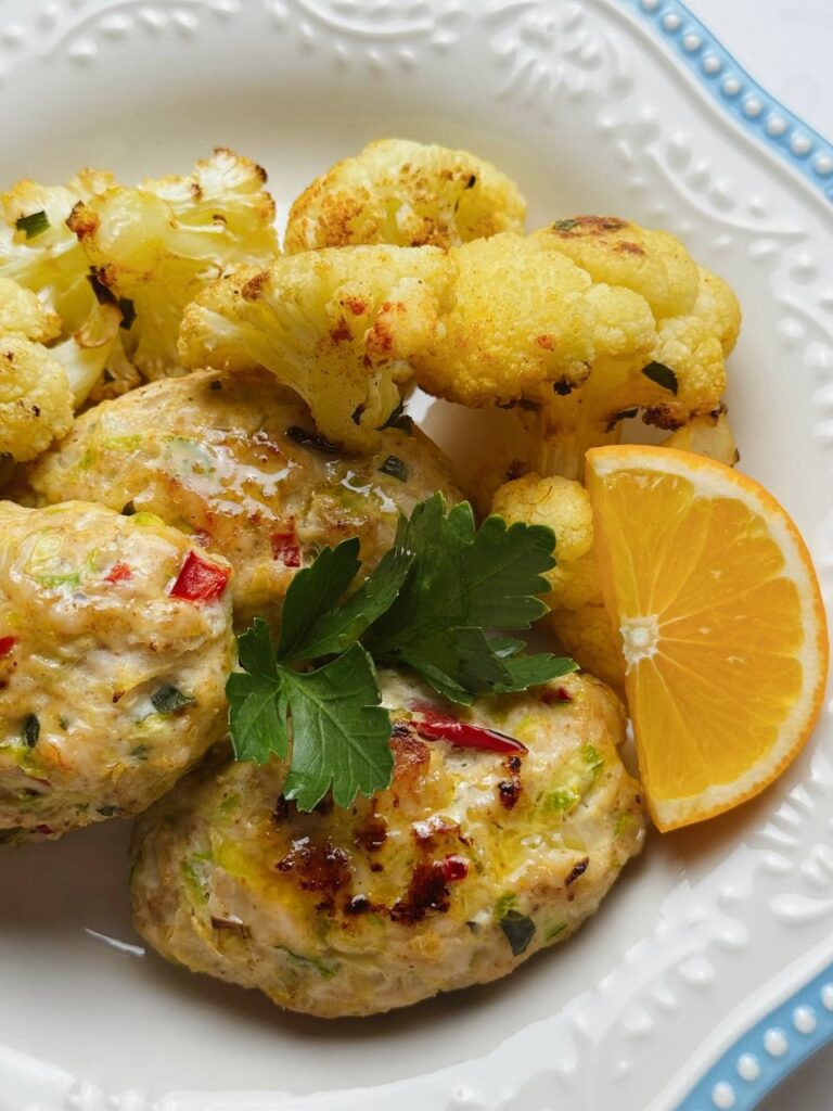 Close-up of fritters served with roasted cauliflower, lemon, and parsley