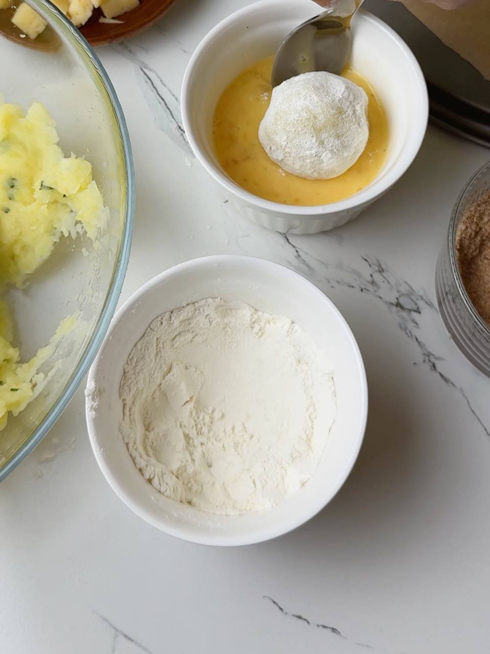Potato croquette being coated in flour and egg