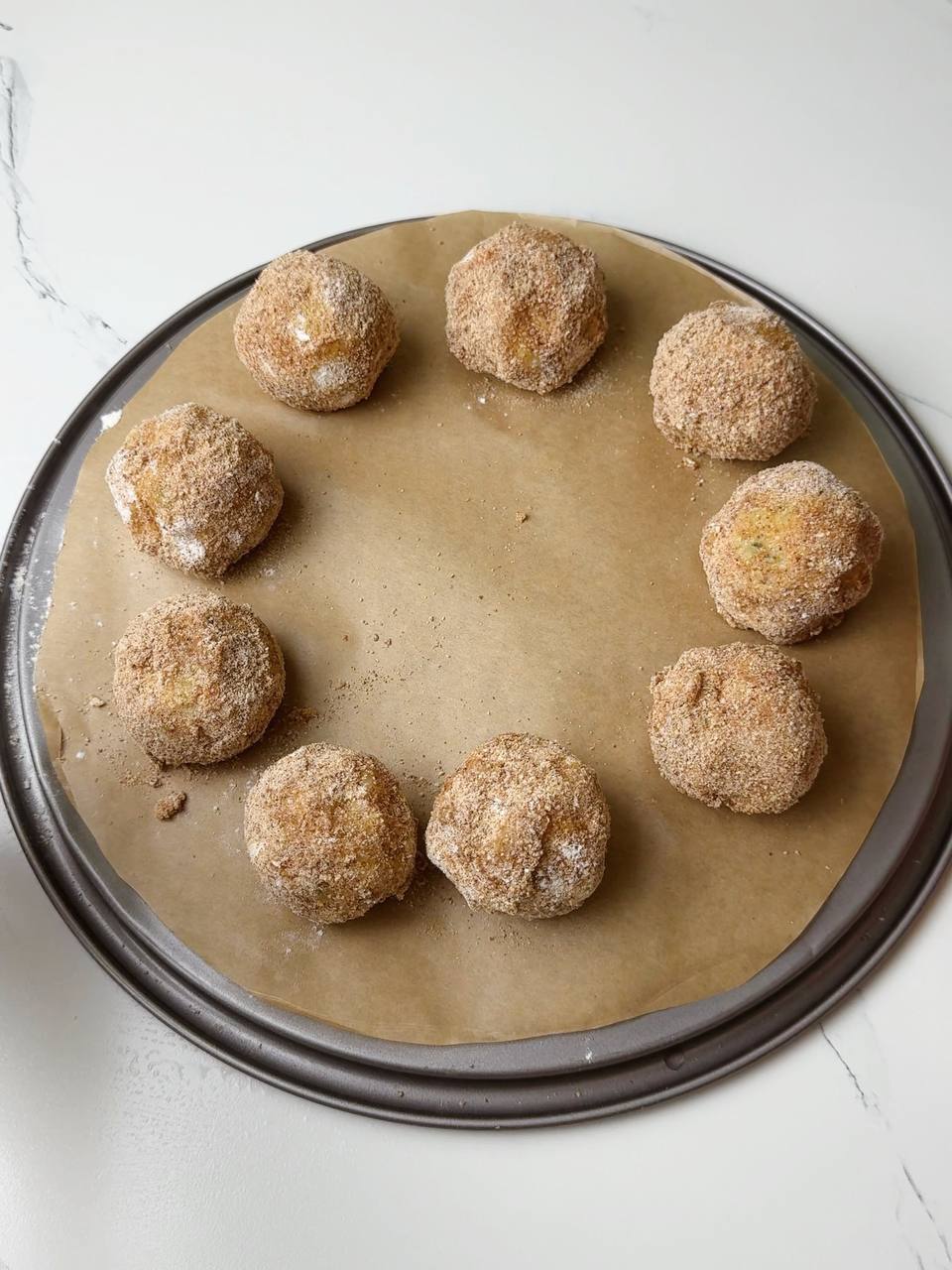 Shaped potato croquettes on a parchment-lined tray before baking