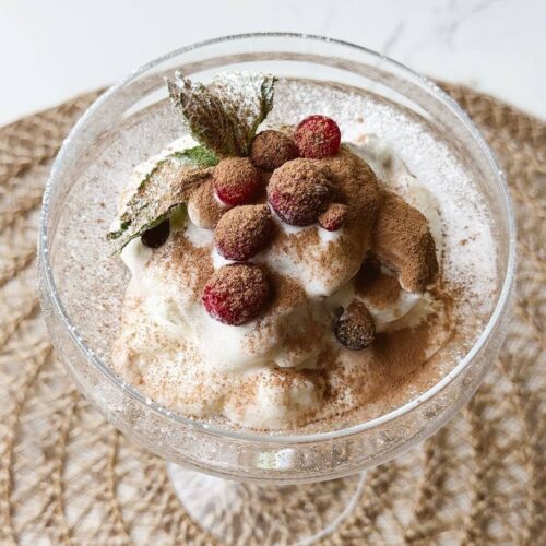 Chocolate ice cream decorated with cocoa powder, fresh berries, and mint leaves.