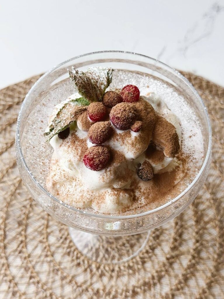 Chocolate ice cream decorated with cocoa powder, fresh berries, and mint leaves.