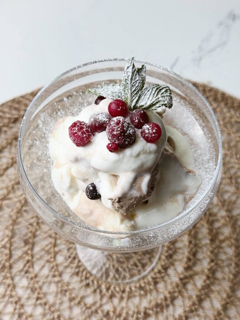 Ice cream decorated with powdered sugar, fresh berries, and mint leaves.