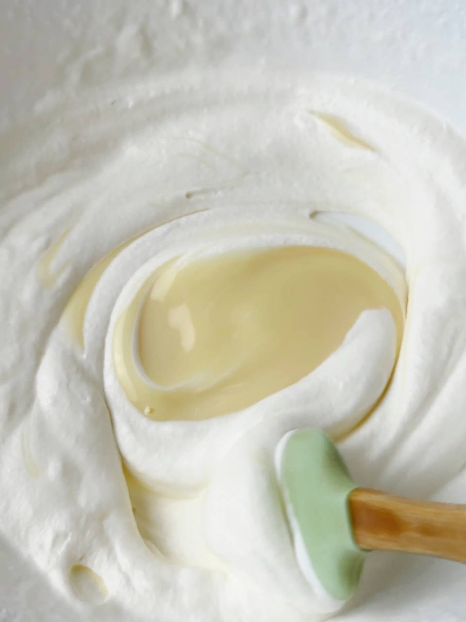 Folding sweetened condensed milk into whipped cream to make ice cream base.