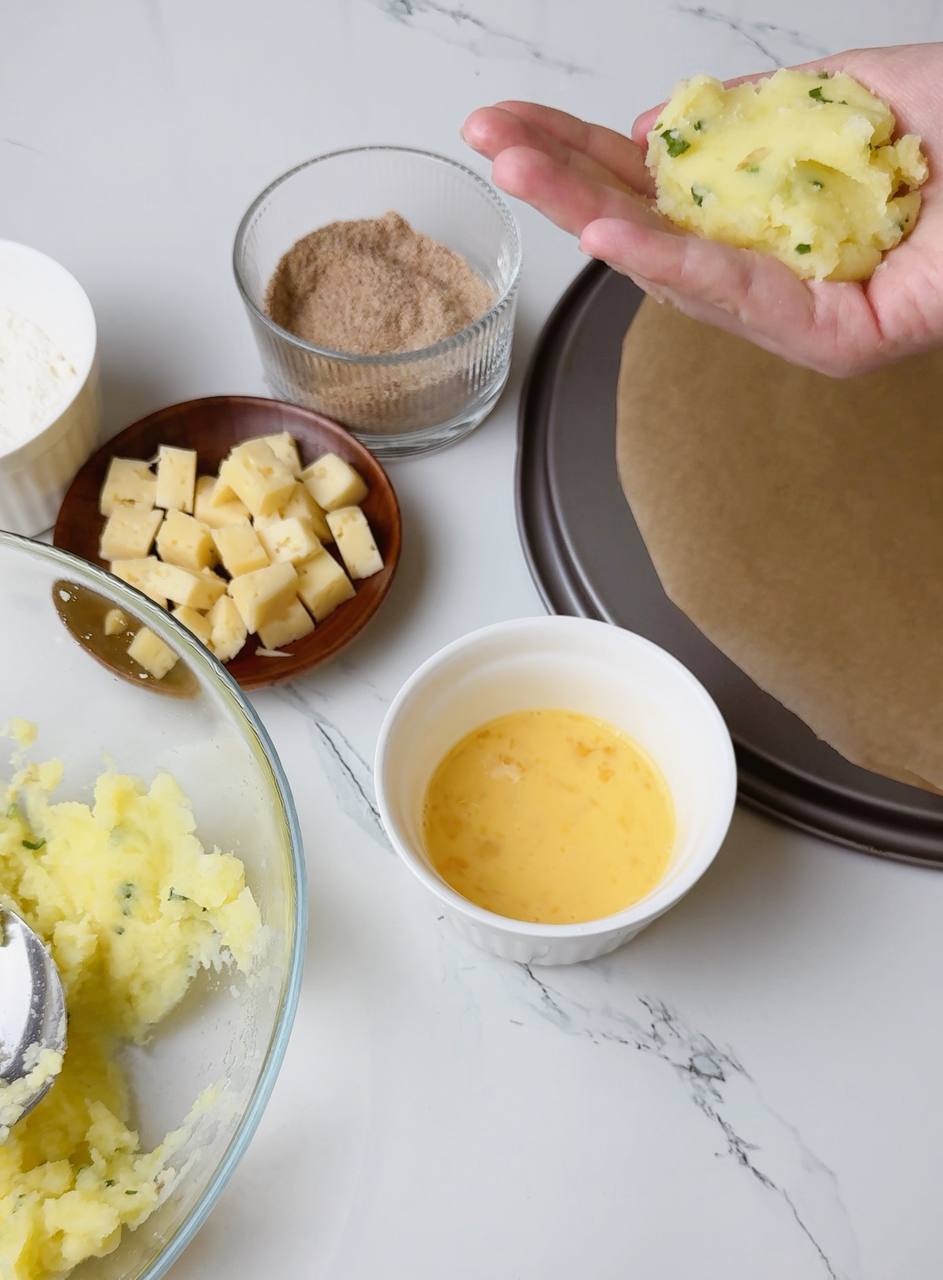 Spoonful of mashed potato mixture with cheese center in hand