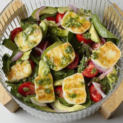 Grilled halloumi salad served with cherry tomatoes, avocado, arugula, and basil vinaigrette