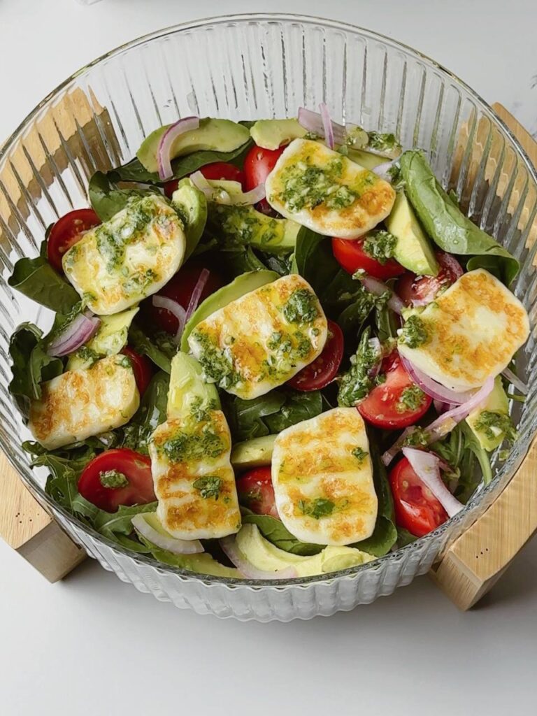 Grilled halloumi salad served with cherry tomatoes, avocado, arugula, and basil vinaigrette