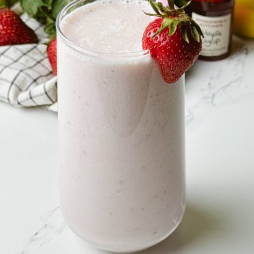 Creamy strawberry banana milkshake served with straw and strawberry garnish.