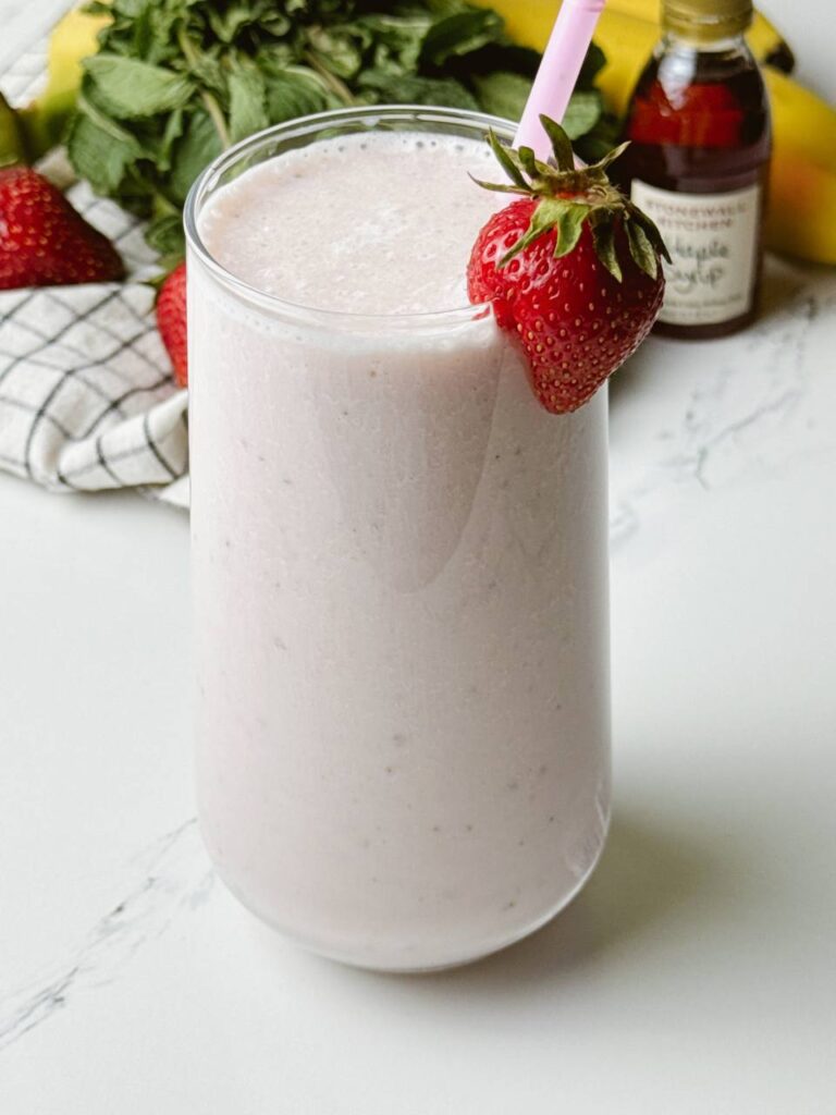 Creamy strawberry banana milkshake served with straw and strawberry garnish.