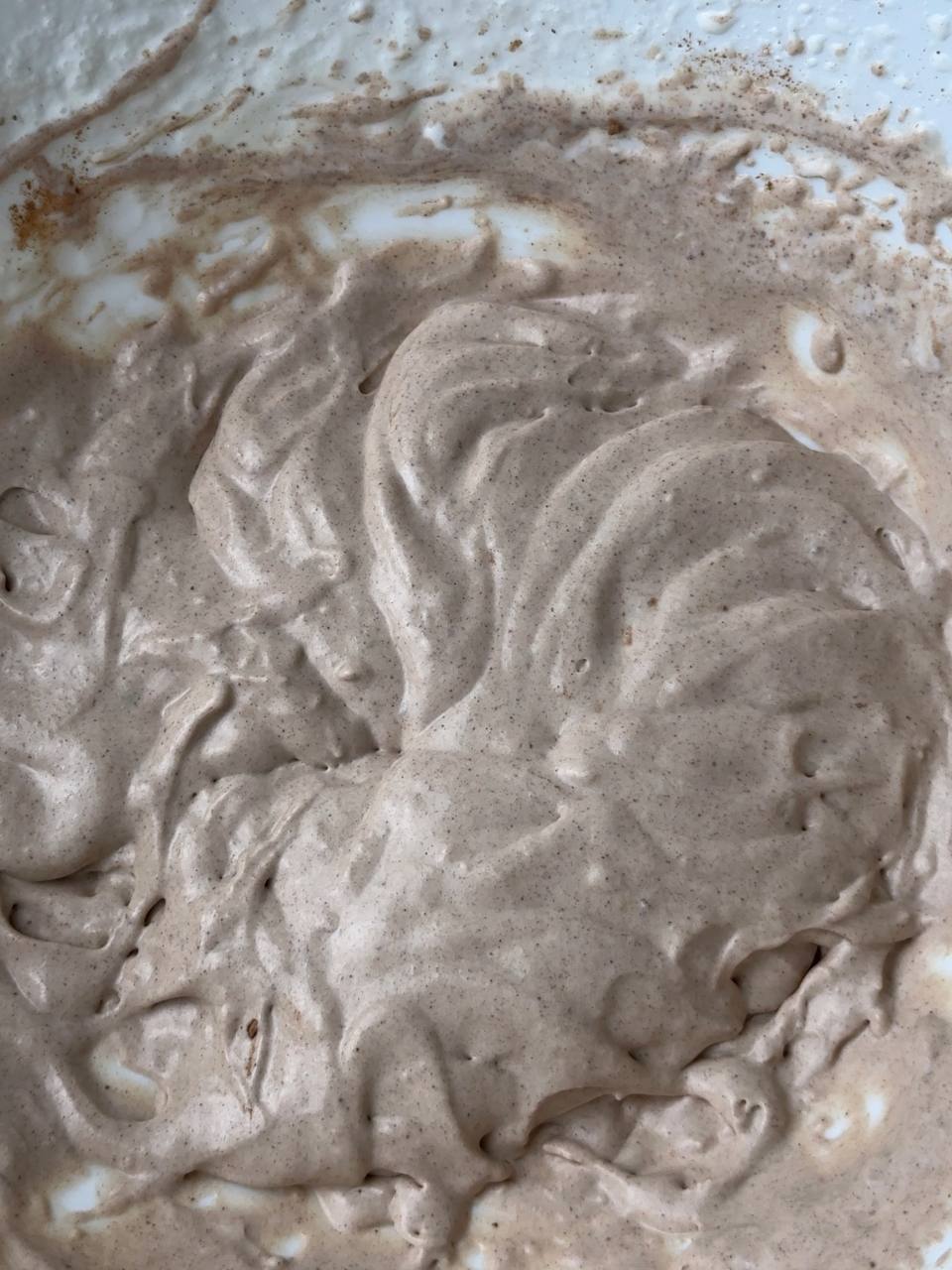 Gently folding cocoa powder into ice cream mixture for chocolate flavor.