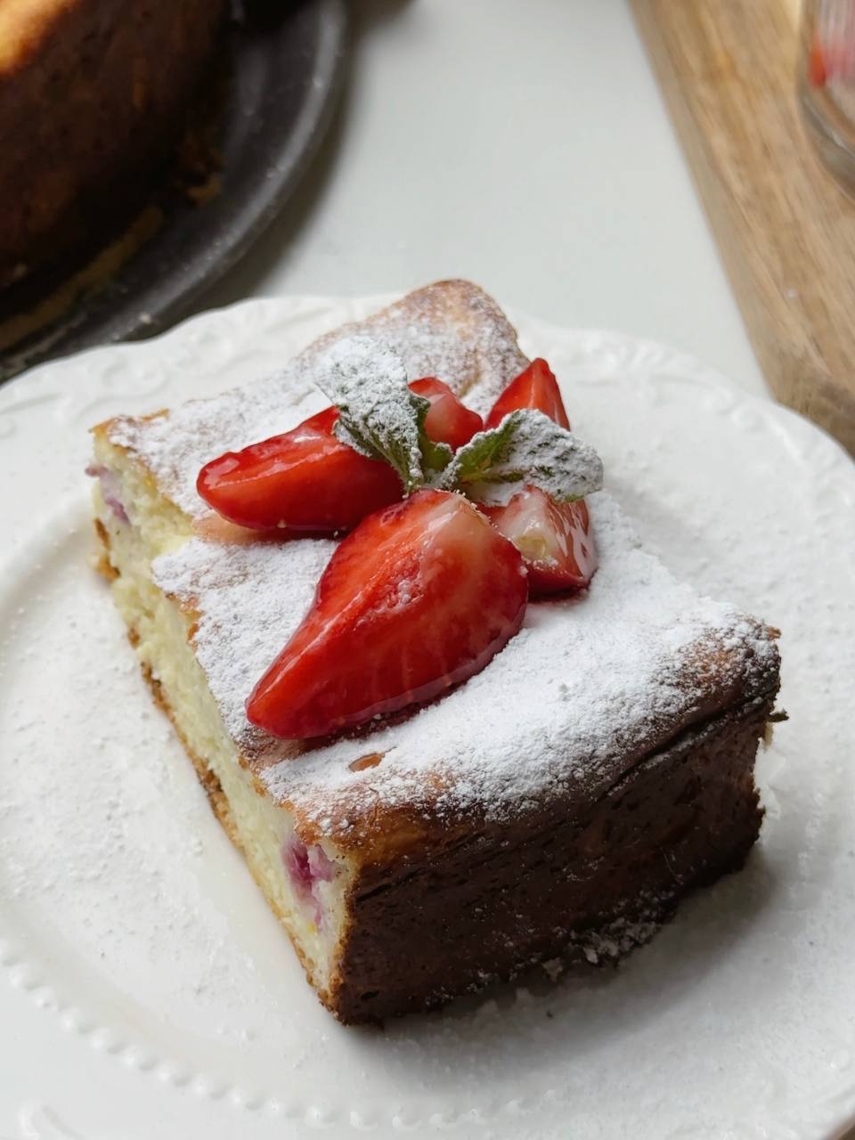 Close-up of cottage cheese dessert slice with strawberries, mint, and powdered sugar