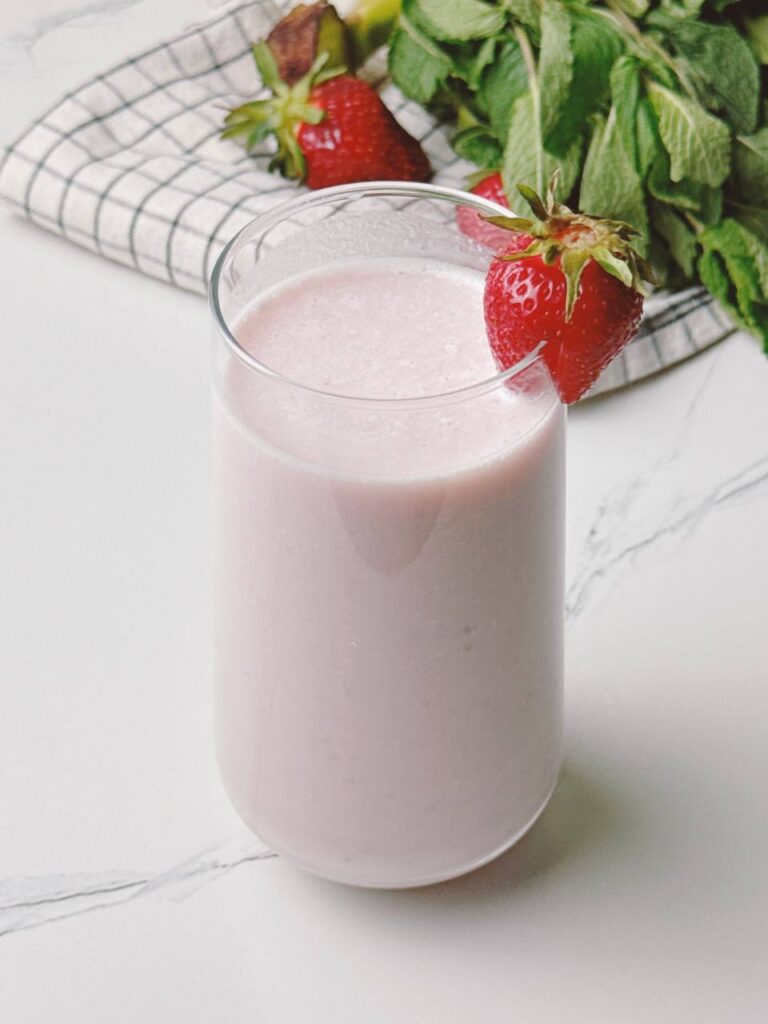 Strawberry banana milkshake served in glass, topped with a fresh strawberry.