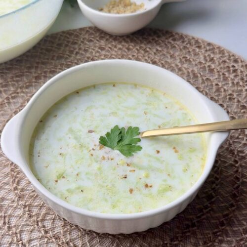 Bowl of cold Tarator yogurt cucumber soup served with parsley and a spoon