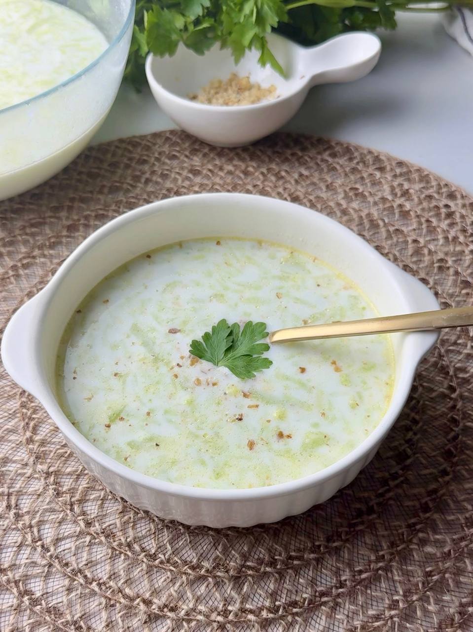 Bowl of cold Tarator yogurt cucumber soup served with parsley and a spoon