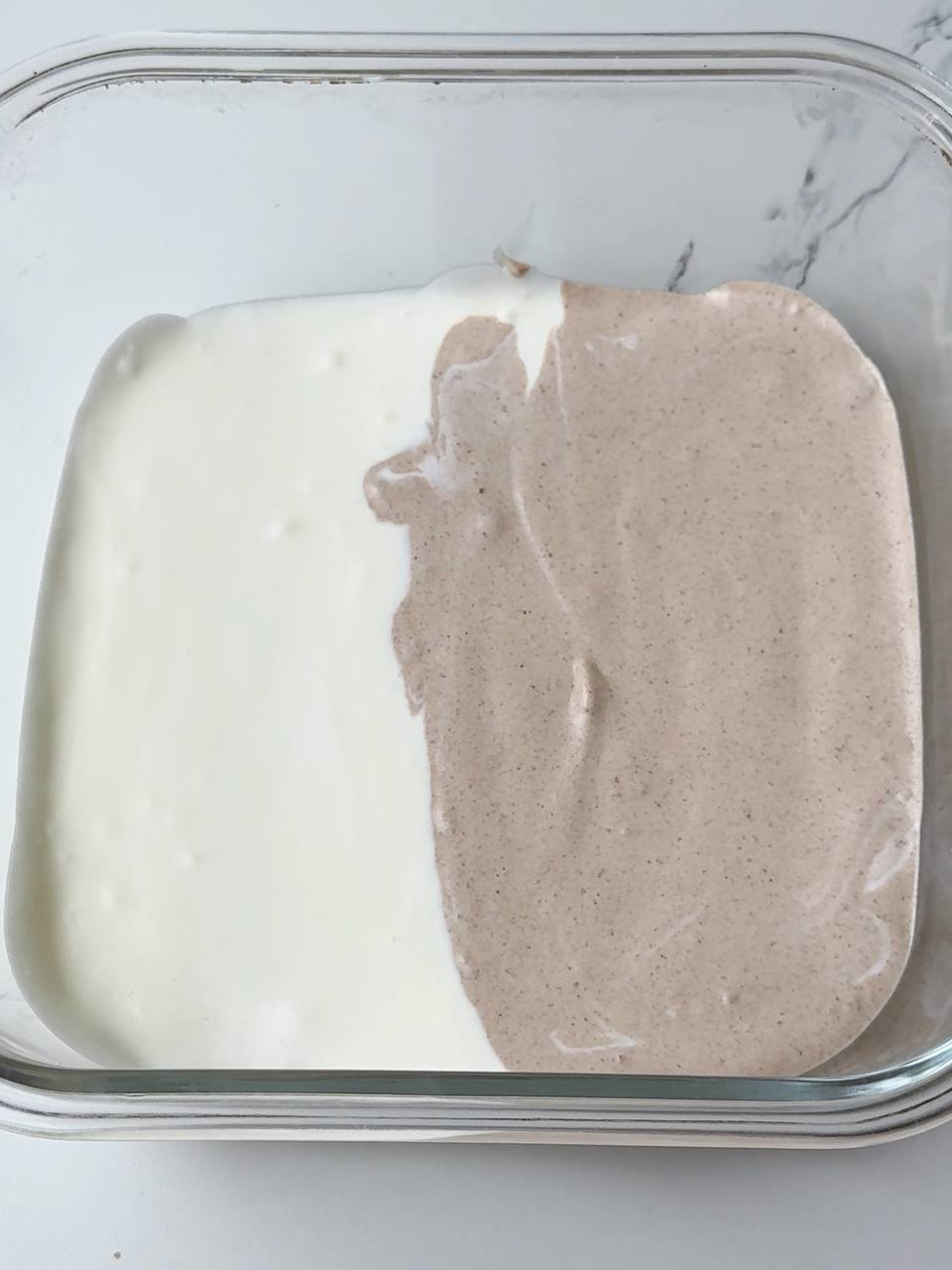 Vanilla and chocolate ice cream mixtures side by side in one freezer container.