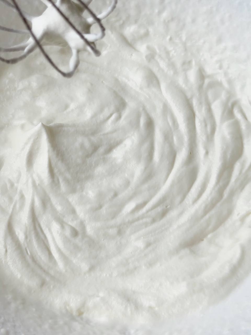 Whipping cold heavy cream to soft peaks for ice cream base.